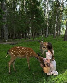 a woman kneeling down next to a deer