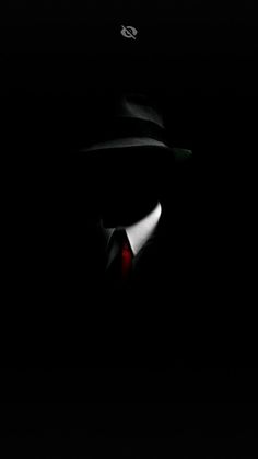 a man wearing a hat and tie in the dark