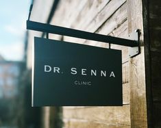 a sign hanging from the side of a wooden building that says dr sehna clinic