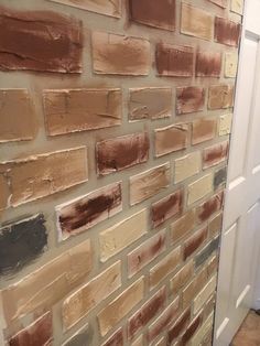 a bathroom with a white toilet and brown brick wall next to a door in the corner