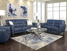 a living room filled with blue furniture in front of a brick wall and wooden floors