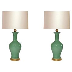 two green vases with white lamps on them are sitting side by side in front of each other