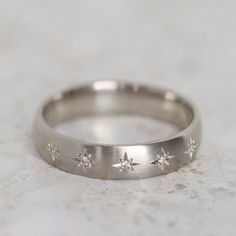 a wedding ring with five stars on the side, sitting on a marble countertop