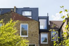 a row of brick houses with windows on the top and second story, in front of trees