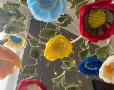 multicolored flowers hanging from the ceiling in front of a window with light bulbs