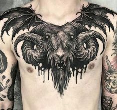 a man with tattoos on his chest has a demon head and wings tattoo on his chest