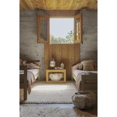 two beds in a small room with wooden paneling and windows overlooking the trees outside