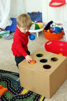 a young boy playing with an open cardboard box