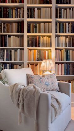 a white chair sitting in front of a book shelf filled with books