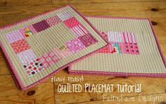 two quilted placemats sitting on top of a wooden floor next to each other