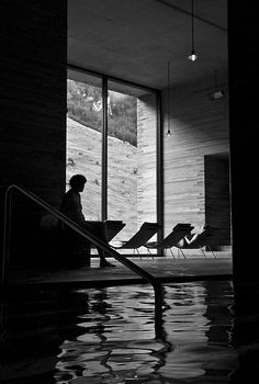 a woman sitting on an escalator next to a swimming pool in a building