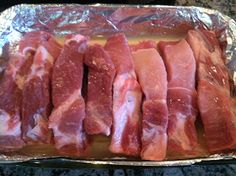 raw meat sitting on top of tin foil in a baking pan, ready to be cooked