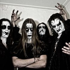 group of people with painted faces and makeup on posing for the camera in front of a white wall