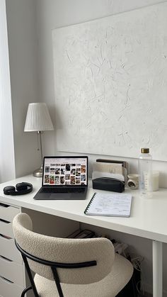 a laptop computer sitting on top of a white desk next to a lamp and chair