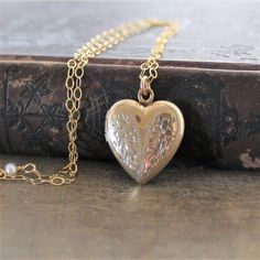 This vintage locket is engraved with a floral design on the front; the reverse is plain.  The heartshaped pendant opens revealing two compartments in which to place your favorite photos.  The locket hangs from a new 14k gold filled textured chain accented with tiny pearls the clasp.    ★Personalize the locket with our charms:https://www.etsy.com/shop/lexiandgem?section_id=6307004Locket 24x20mmNecklace length 18" (45cm)✦All of our vintage lockets ship with complimentary insurance✦✤Our entire sele Gold Heart Locket Necklace, Locket Gold, Push Present, Gold Heart Locket, Gold Locket Necklace, Vintage Locket, Wedding Jewelry For Bride, Picture Locket, Heart Locket Necklace