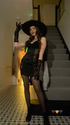 a woman in a black dress and hat posing for the camera