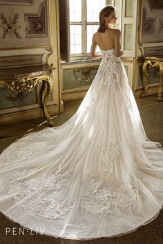 a woman in a wedding dress standing by a window with her back to the camera