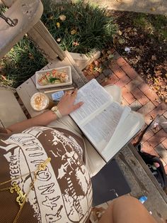 a person sitting at a table with an open book and food in front of them