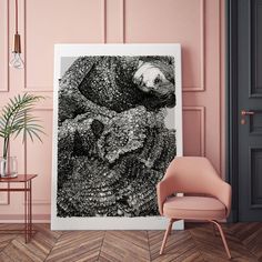 a black and white photo hanging on the wall next to a chair in a pink room