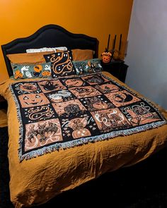 a bed with an orange comforter and black headboard, decorated with halloween decorations