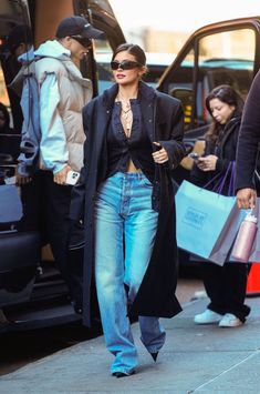 a woman is walking down the street with shopping bags in her hand and another person wearing sunglasses