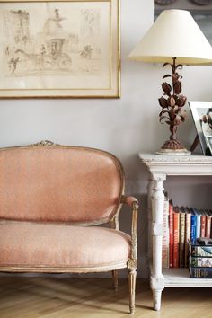 a living room filled with furniture and a lamp on top of a wooden floor next to a book shelf