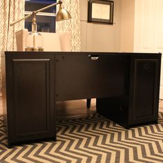 a black desk sitting on top of a rug in front of a wall mounted lamp