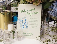 there is a card on the table next to some candles and vases with flowers