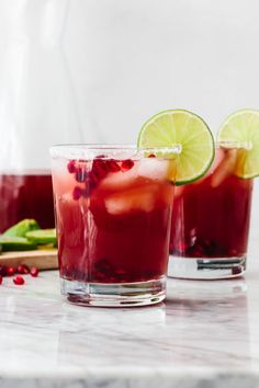 two glasses filled with pomegranate and garnished with lime