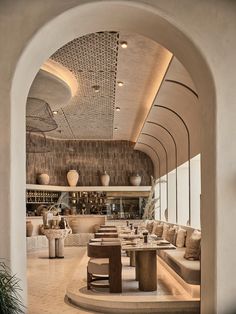 the interior of a restaurant with tables and couches in front of an arched doorway