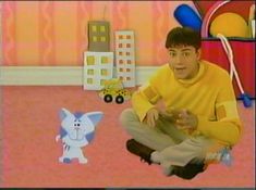 a young man sitting on the floor in front of a tv screen with an animated cat