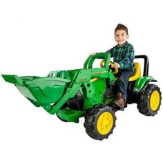 a young boy riding on the back of a green toy tractor