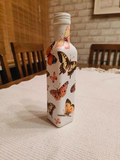 a bottle with butterflies on it sitting on a bed