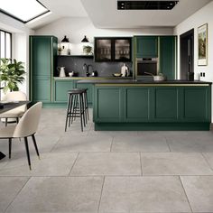 a large kitchen with green cabinets and counter tops in an open floor plan, along with two bar stools