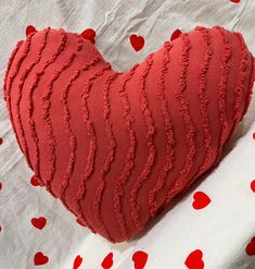 a red heart shaped pillow sitting on top of a bed