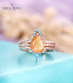 a ring with an orange and blue stone in it on top of a turquoise surface