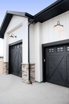 two black and white garage doors on the side of a house with brick pillars in front of them