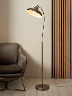 the floor lamp is next to a chair in front of a wall with wood slats