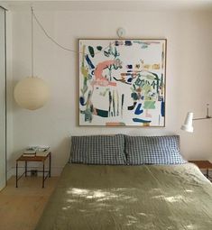 a bed sitting under a painting on top of a wall