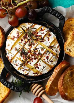 a pan filled with food next to bread and grapes