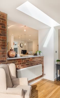 a living room filled with furniture next to a brick wall and wooden floored floors