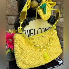 a yellow purse sitting on top of a table next to a brick wall with a welcome sign