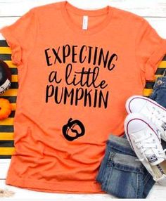 an orange shirt with the words expecting a little pumpkin on it next to some pumpkins