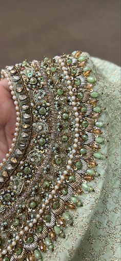 a close up of a person's hand holding a piece of beaded jewelry