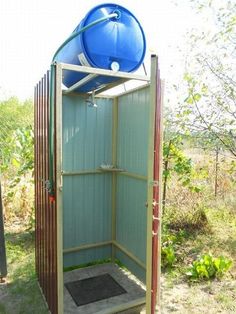 an outdoor shower with a blue water tank on the top and bottom part of it