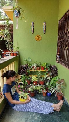 a woman is sitting on the porch with potted plants