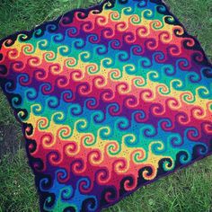 a multicolored blanket is laying on the grass