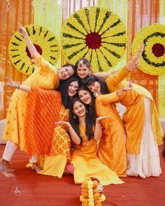 a group of women standing next to each other in front of a flower arrangement on the ground