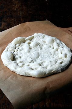 an uncooked pizza dough sitting on top of a piece of waxed paper