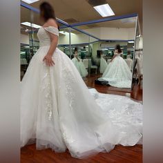 a woman standing in front of a mirror wearing a wedding dress